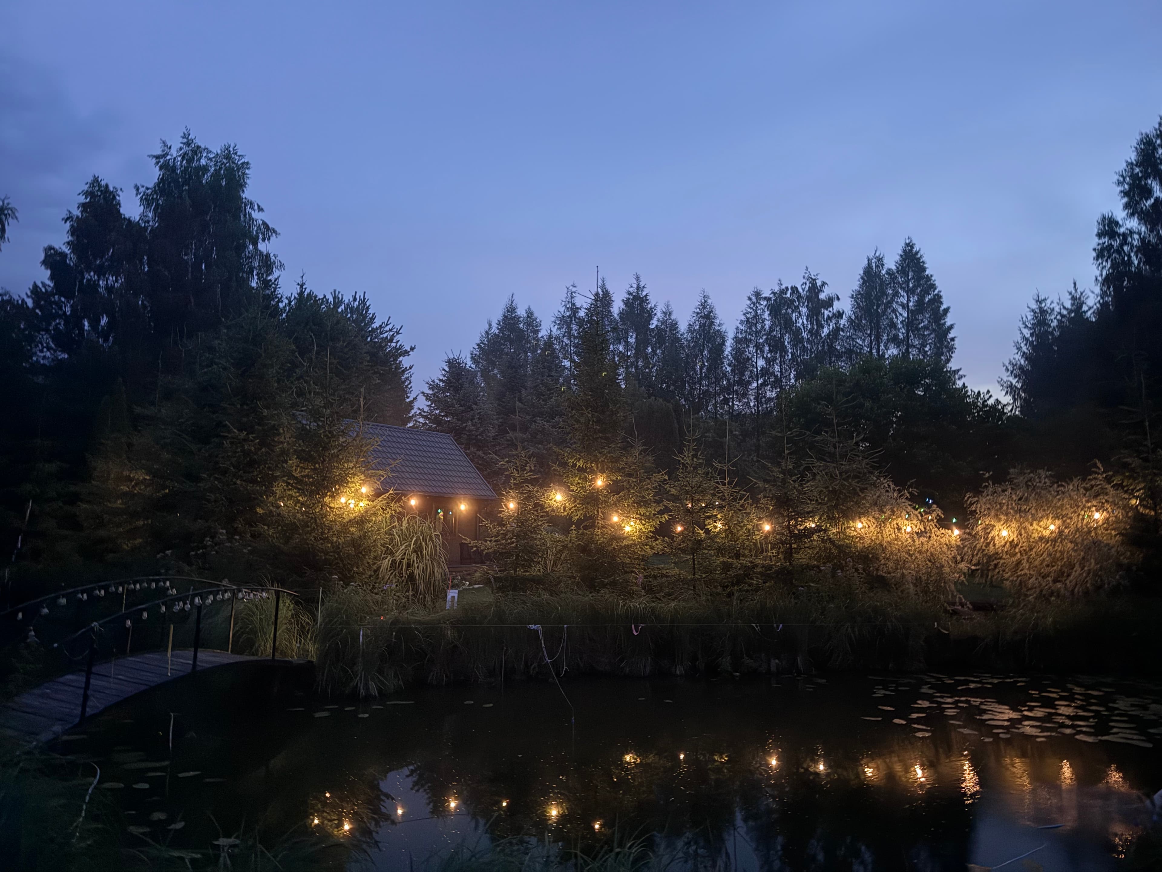 Domek nocą z lampkami nad stawem